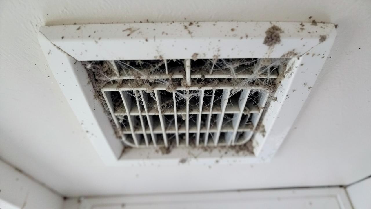 Ceiling Supply Register Cleaning, Before: Ceiling air vent caked with gray dust and cobwebs along the louvers